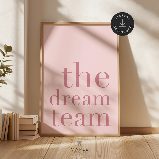 Teamwork poster with quote 'the dream team' in large dark pink letters on a pale pink background. Minimalist style. Shown in a wood frame leaning on a wall.