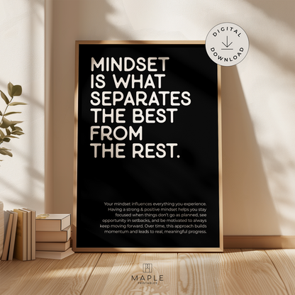 This image shows a framed motivational poster with the large words “Mindset is what separates the best from the rest” in the top left corner, and a longer paragraph at the bottom in a smaller font size. The print features bold white lettering on a black background and is displayed in a light wood frame. It’s styled in a warm, neutral space with soft sunlight and a plant nearby. A small circle in the corner says “Digital Download.”