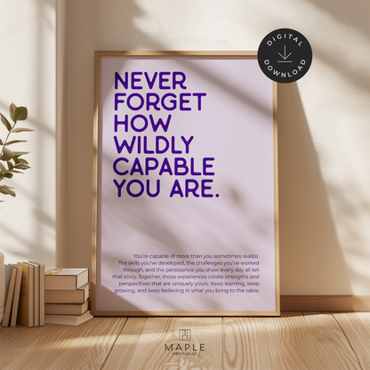 Motivational poster featuring the quote 'Never forget how wildly capable you are' in dark purple letters on a pale purple background. Minimalist design style. Shown in a wood frame leaning against a wall.